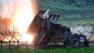 ATACMS missiles are seen during South Korea-US military exercises, surrounded by barbed wire fencing and lush greenery in the background. 