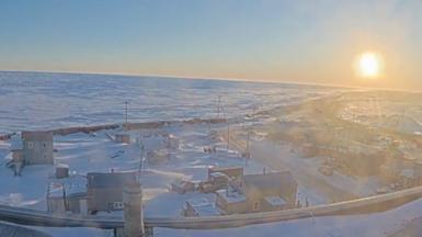 Utqiagvik, Alaska is seen with the sun in the sky.