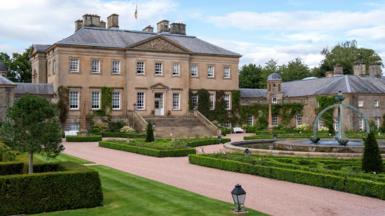 Dumfries House, a large sandstone building surrounded by landscaped gardens.