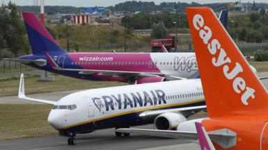 A Wizz Air, Ryanair and Easyjet plane on an airport airfield.