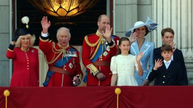 Members of the Royal Family stand on the Buckingham Palace balcony and wave. From left to right: Queen Camilla and the King, the Prince and Princess of Wales, and Princess Charlotte, Prince George and Prince Louis