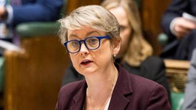 Yvette Cooper giving statement from in the House of Commons. Colleagues can be seen sitting in the rows of benches behind her.