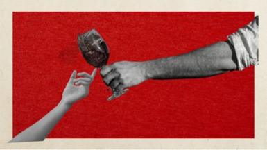 Hand reaching out for glass of alcohol against red backdrop
