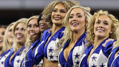 Smiling members of the Dallas Cowboys Cheerleaders standing in their uniforms in a row