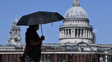 A woman walks under an umbrella past St Paul's Cathedral in London during the heatwave.
