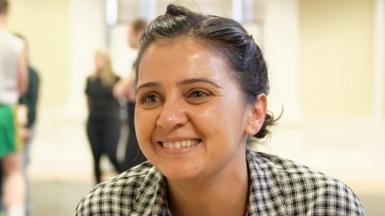 A smiling Natalie Davies, a Bradford-born actor and writer. She is wearing a black and white checked shirt and has her black hair tied back.