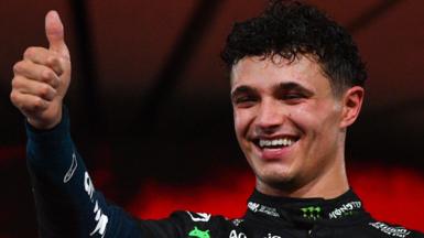 Lando Norris makes the thumbs-up gesture on the podium after the Abu Dhabi Grand Prix