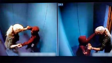 Woman with long blonde hair tied in a pony tail with a boy wearing a red hooded top inside a blue padded room. 