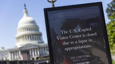 A sign outside the US Capitol advises visitors about the government shutdown in Washington, DC, and says the Capitol Visitor Center is closed. Congress is seen in the background. 