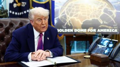 Donald Trump in the Oval Office in front of a Golden Dome poster