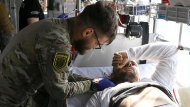 Paramedics from Ukraine's Hospitallers organisation check on servicemen wounded in battles in the Donetsk region, now on a medical evacuation bus in an undisclosed location, as they are driven to a bigger hospital on September 23, 2024