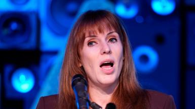 Angela Rayner speaks into a microphone against the backdrop of speakers at a Liverpool night club