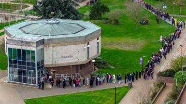 Staff and students, some wearing face masks, queue to receive antibiotics at the University of Kent in Canterbury after an outbreak of meningitis caused the deaths of two people, on March 16, 2026 in Canterbury, United Kingdom.
