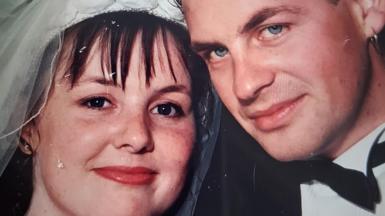 The couple are pictured at their wedding. Murdina is wearing her wedding dress. Archie is wearing a black jacket, bow tie and a white shirt. They are smiling into the camera.