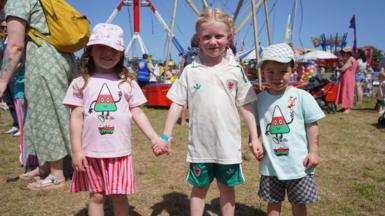 Erin, Betsi ac Efan yn mwynhau'n y ffair yn eu crysau ti Mistar Urdd a chit pêl-droed Cymru