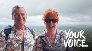 Ardon and Debbie Rainbird on holiday with a forest view behind them.