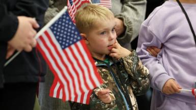 People from the first group of white South Africans granted refugee status in the US hold US flags as they attend a meet and greet event, at Dulles International Airport