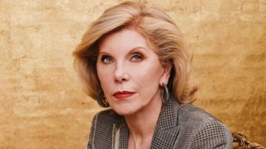 Christine Baranski sitting in front of a gold background