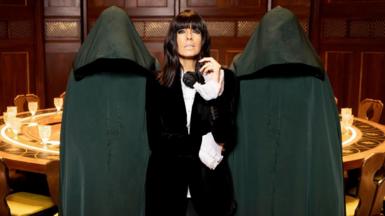 Claudia Winkleman surrounded by anonymous green-cloaked Traitors 