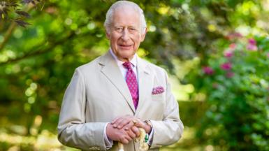King Charles in a summer suit holds a shepherd's crook