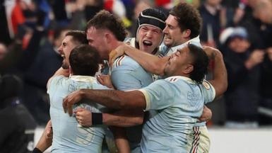 Thomas Ramos is mobbed by his France team-mates after landing the final kick to claim victory