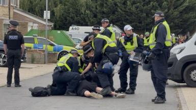A group of police around a man being arrested on the ground.