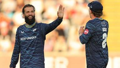 Yorkshire player Moeen Ali smiles and holds up his hand in celebration as he is approached by team-mate Dom Bess.