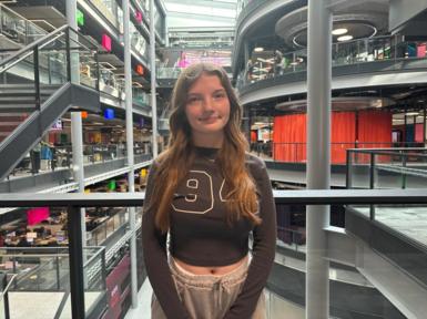 Mia is smiling at the camera. She is stood on the balcony in the BBC Wales building in Cardiff