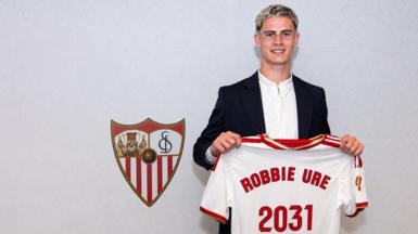 Robbie Ure holding the Sevilla shirt in front of the badge