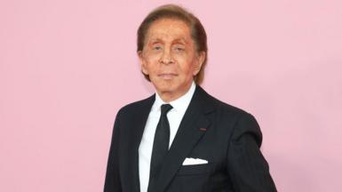 Valentino Garavani attends the 2019 CFDA Fashion Awards at The Brooklyn Museum on June 3, 2019 in New York City wearing a black suit and standing against a pink backdrop 