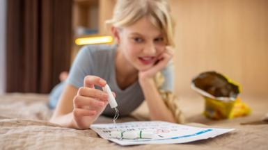 Young girl on bed holding tampon 