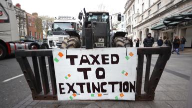 A sign that says taxed to extinction on the front of a tractor 