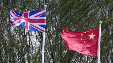 The Union Flag and Chinese Flag on flagpoles in front of trees