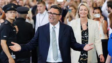 A beaming Andy Burnham spreads his arms wide as he emerges from a crowd of Labour MPs