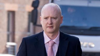 Graeme Dott arriving at the High Court in Glasgow. He is wearing a dark suit over a pink shirt witha pink tie.