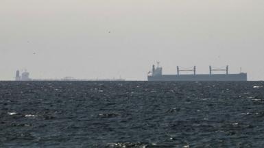 A cargo ship is seen on the horizon in the Gulf, near the Strait of Hormuz