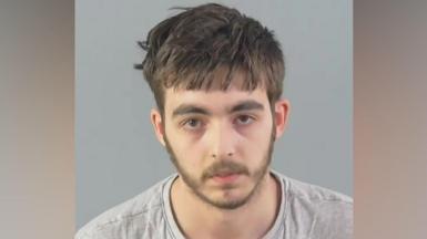 Carlo Tritta, who is wearing a grey jumper, is staring directly at the camera in this custody mugshot. He has straight, light brown hair and a thin beard.