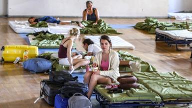Tourists and local residents from the resort village of Agia Galini gather in an indoor stadium where they are temporarily accommodated during a wildfire in Rethymno area, in the southwest of the Greek island of Crete on July 30, 2026. 