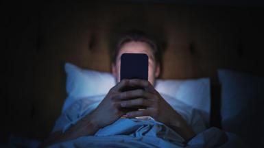 A man looking at his phone in bed