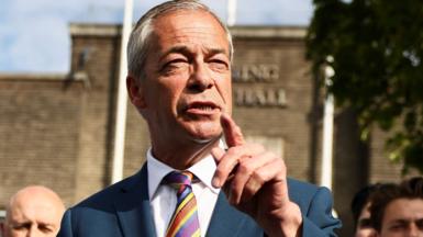 Close up of Nigel Farage talking to the press. He is wearing a blue suit and a colourful tie