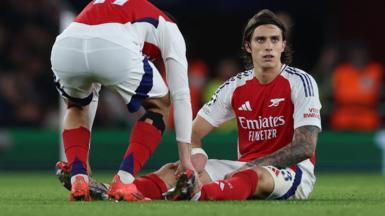 Arsenal's Riccardo Calafiori sits on the pitch