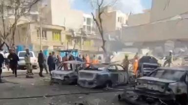 People gather near burnt vehicles in Tehran after earlier strikes