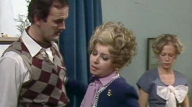 Screengrab from a scene where Sybil is looking at Basil's shirt