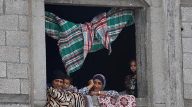 Palestinian women and children look out from a window after US President Donald Trump announced that Israel and Hamas agreed on the first phase of a Gaza ceasefire, in central Gaza, 9 October 2025. 