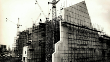 Tall concrete factory building under construction with scaffolding