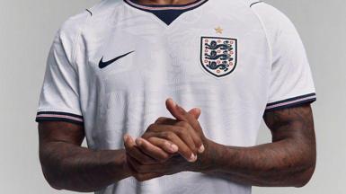 Marcus Rashford clasps his hands while modelling England's white Nike home shirt for the 2026 Fifa World Cup