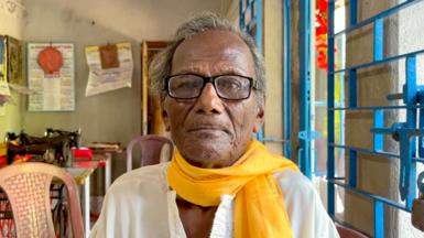 Kanailal Hait, an elderly Indian man who survived the 1943 Bengal famine, wearing a white kurta and yellow scarf