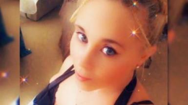 A selfie of a woman with blonde hair and blue eyes. She is looking at the camera.