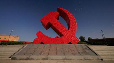 A sculpture of the Chinese Communist Party logo - a hammer and sickle in red.  