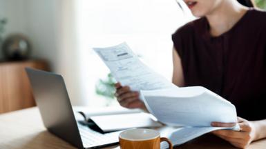 Person looking at bills with a laptop open in front of them